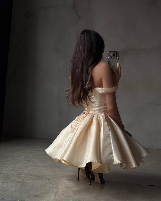 Side view of a model in a champagne A-line off-shoulder dress, showcasing the voluminous skirt.