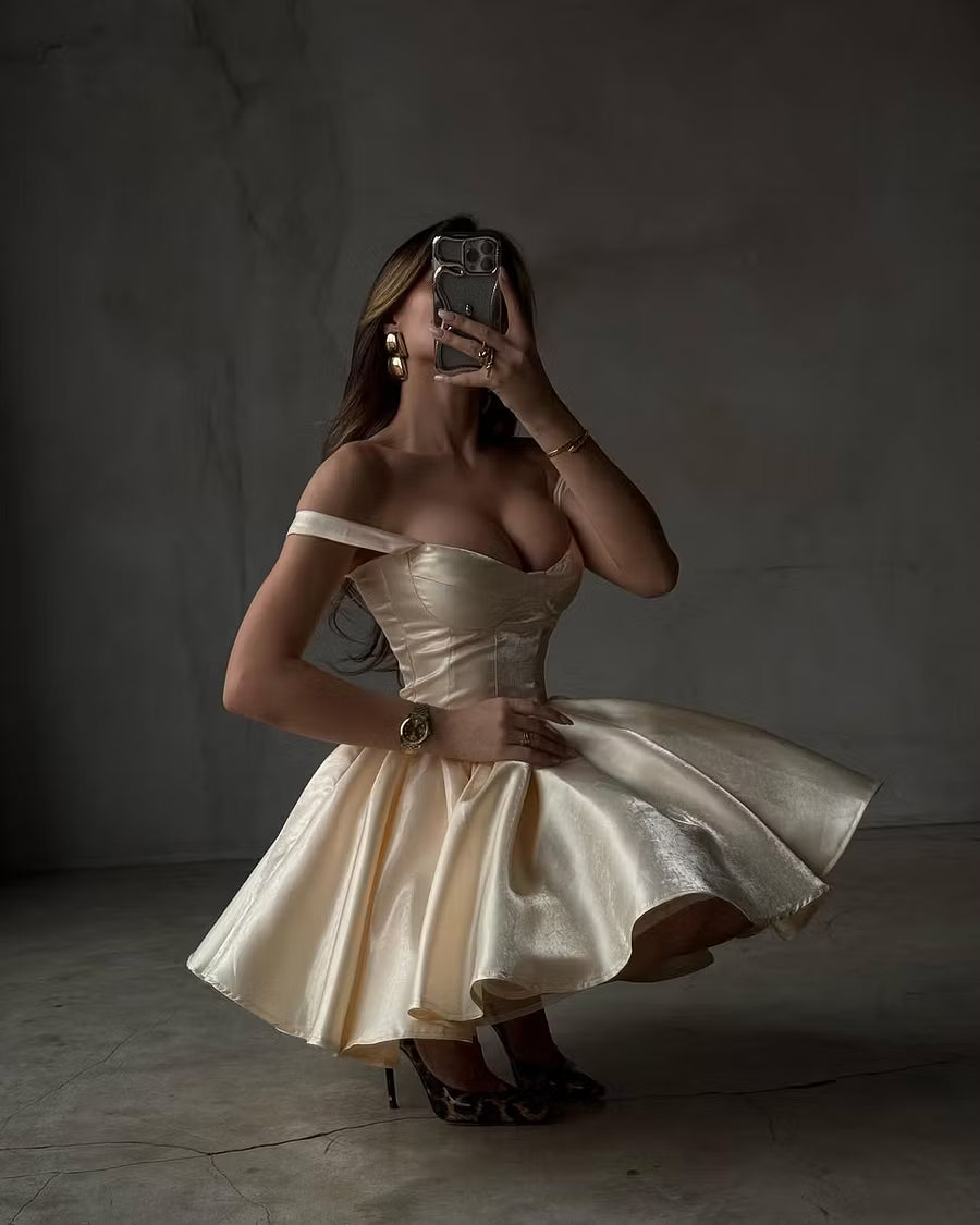 Back view of a model in a champagne A-line off-shoulder dress, highlighting the structured bodice.