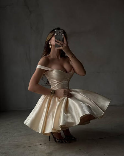Back view of a model in a champagne A-line off-shoulder dress, highlighting the structured bodice.