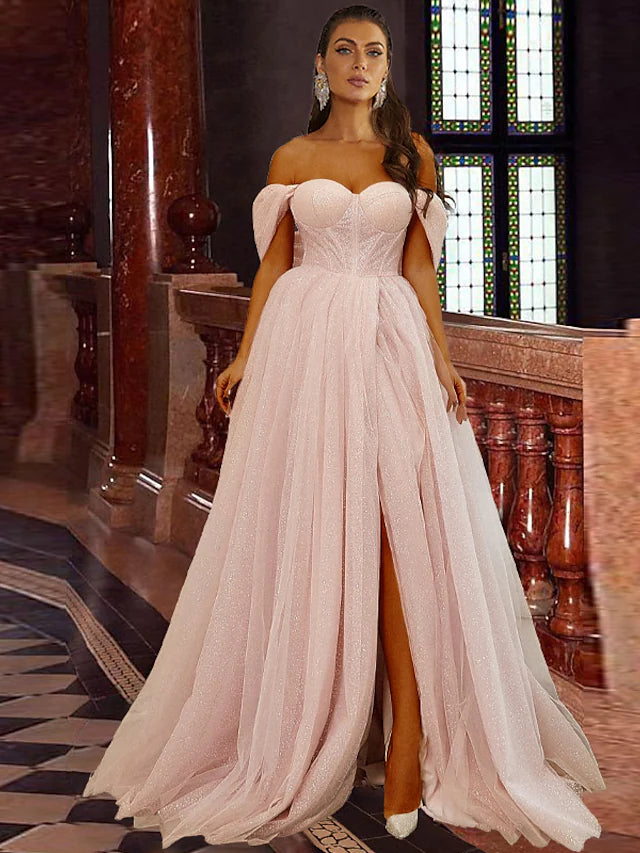 Model wearing a dazzling blue A-line off-shoulder prom dress with glitter tulle and a high slit.