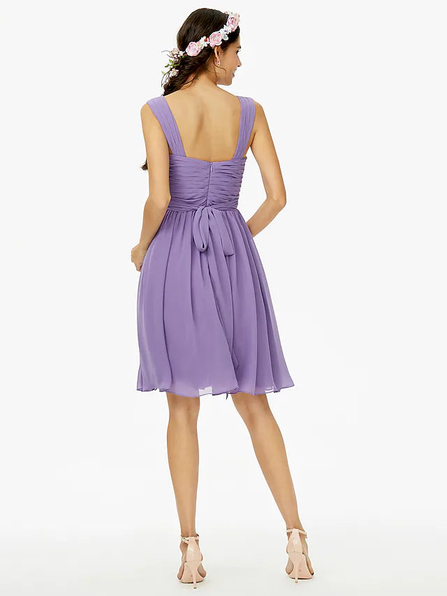 Back view of the blush pink A-line bridesmaid dress, showcasing the open back design and a flowing sash.