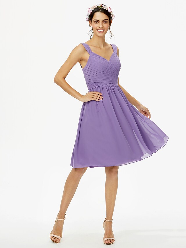 Side profile of a model in a blush pink A-line chiffon knee-length dress, highlighting the fabric and silhouette.