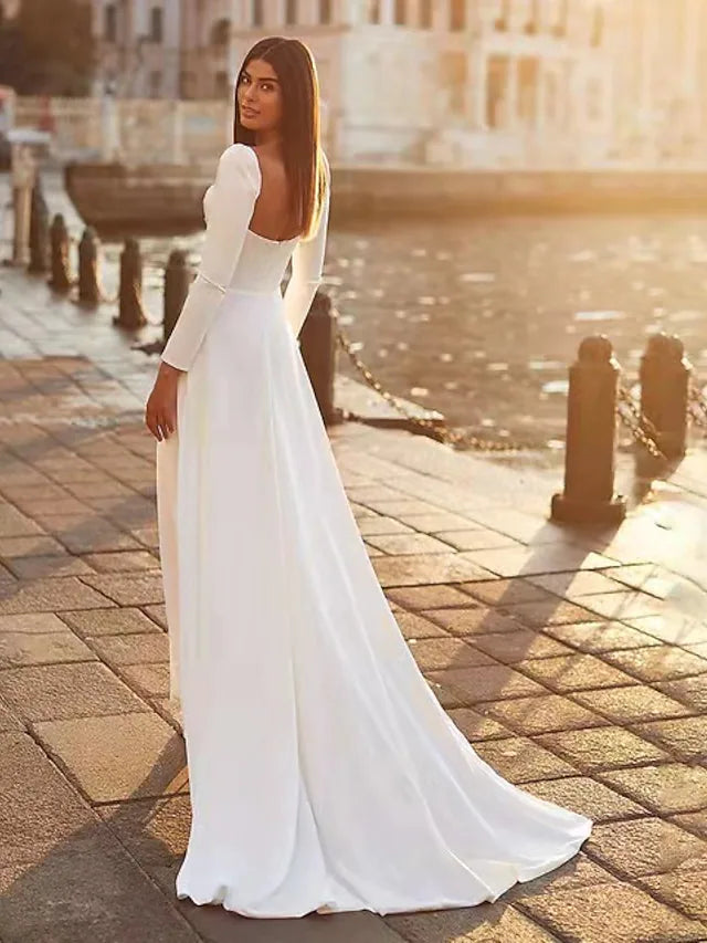 Woman wearing a white A-line long sleeve square neck satin wedding dress.