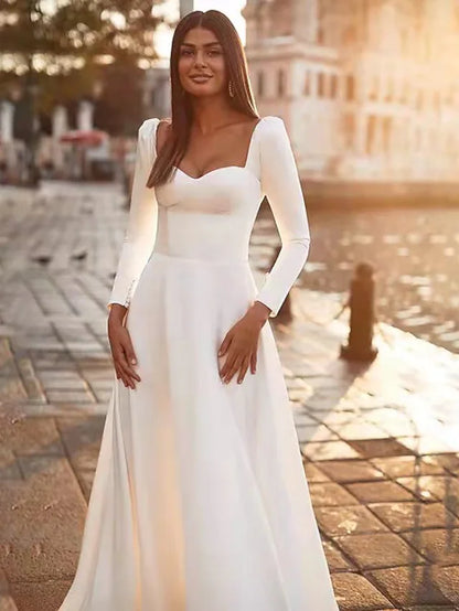 Side profile of a woman in a white A-line long sleeve square neck satin wedding dress.