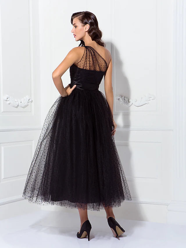 Side profile of a model in a black one-shoulder A-line tulle dress, showcasing the silhouette.