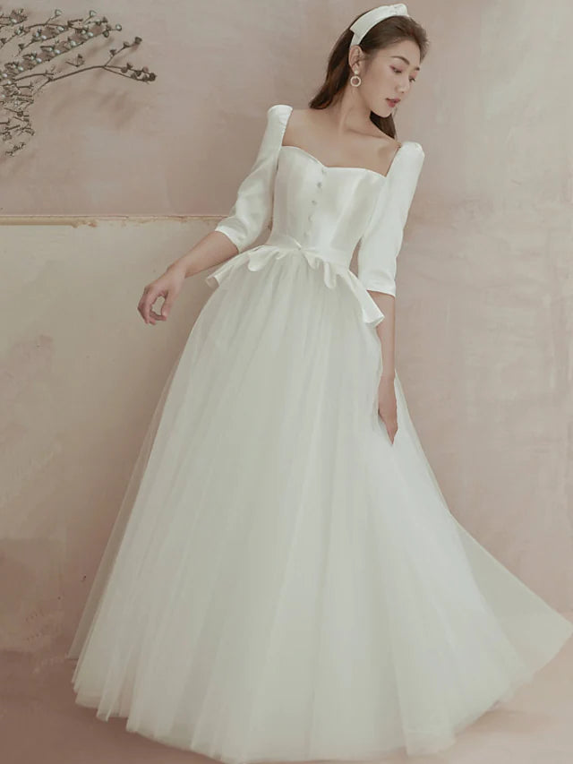 Elegant A-line satin wedding dress with square neck and long sleeves, featuring pleats and ruffles.
