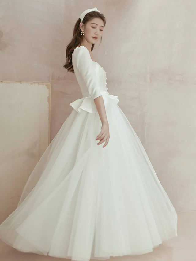 Side view of a bride wearing an A-line satin wedding dress with a square neckline.