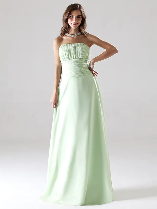 Elegant strapless A-line chiffon bridesmaid dress with ruched draping, worn by a woman standing outdoors.