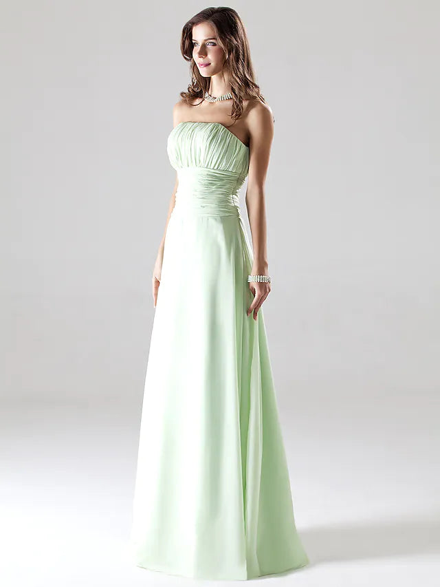 Woman posing in a strapless A-line chiffon bridesmaid dress with ruched draping, hands clasped.