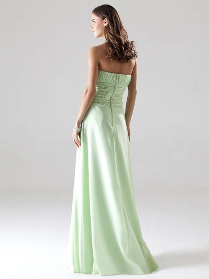 Back view of a woman wearing an elegant strapless A-line chiffon bridesmaid dress with ruched draping.