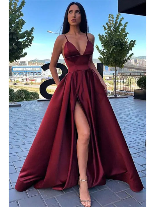 Woman posing in a black satin high split evening dress, side view.