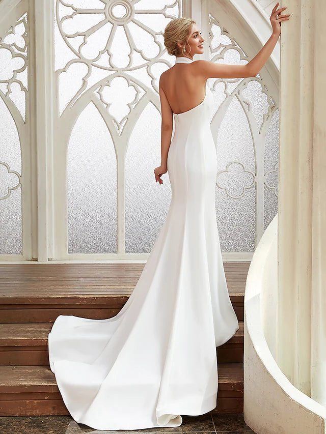 Open back detail of a satin wedding dress with flowing pleats.