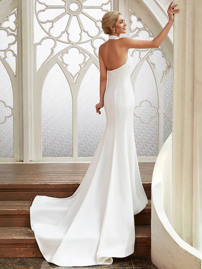 Open back detail of a satin wedding dress with flowing pleats.