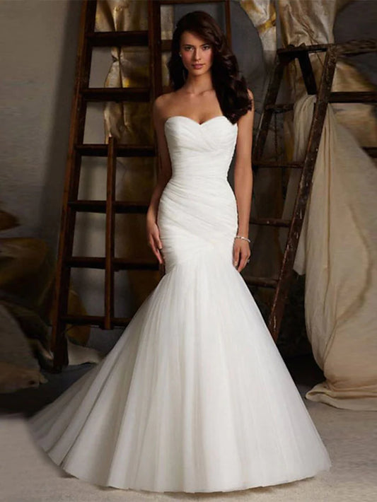 Elegant white mermaid wedding dress with strapless sweetheart neckline, ruched bodice, and court train.