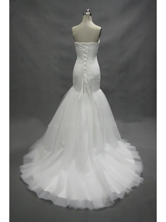 Back view of a white mermaid wedding dress, highlighting the court train and ruched details.