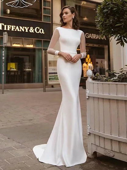 Bride wearing an elegant white mermaid trumpet wedding dress with long sleeves and a jewel neck.