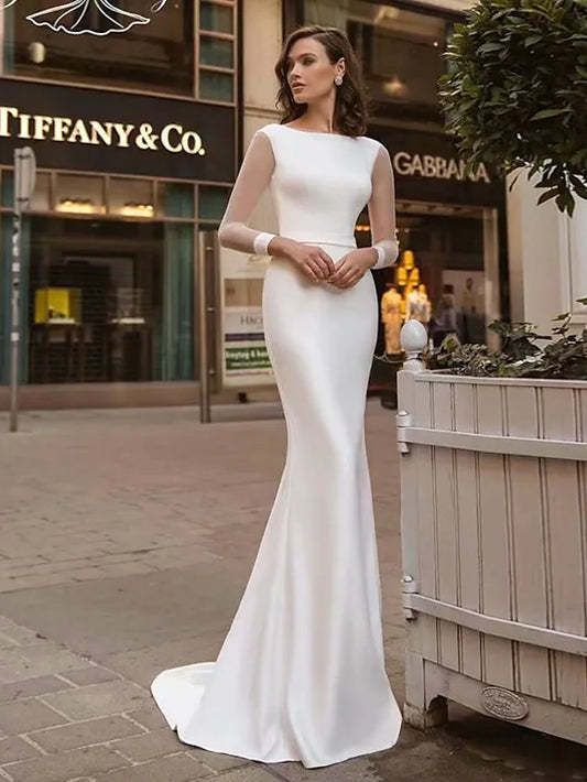 Bride wearing an elegant white mermaid trumpet wedding dress with long sleeves and a jewel neck.
