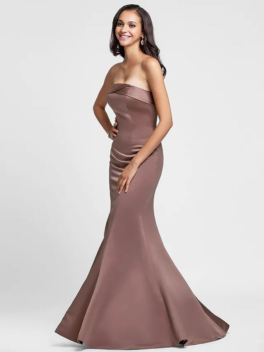 Woman wearing an elegant strapless mermaid trumpet bridesmaid dress with side draping.