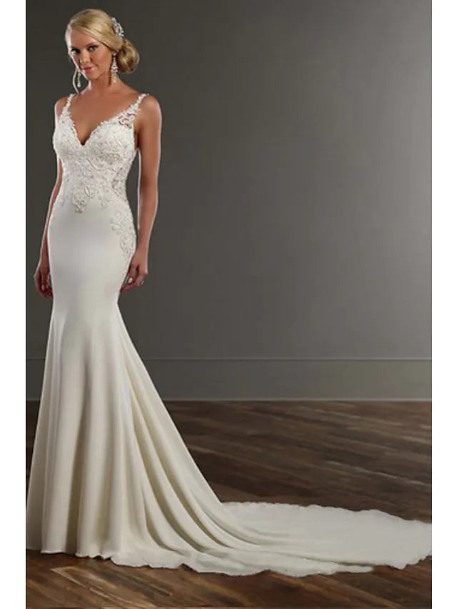 Bride in a white mermaid trumpet wedding dress with spaghetti straps and lace appliques.