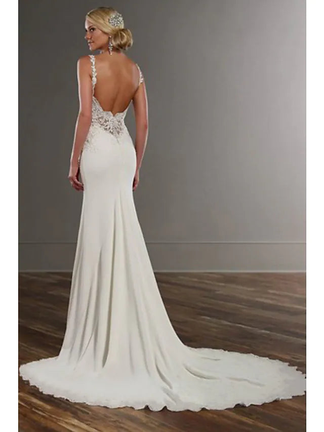 Close-up of the V-neckline and intricate lace appliques on a white wedding dress.