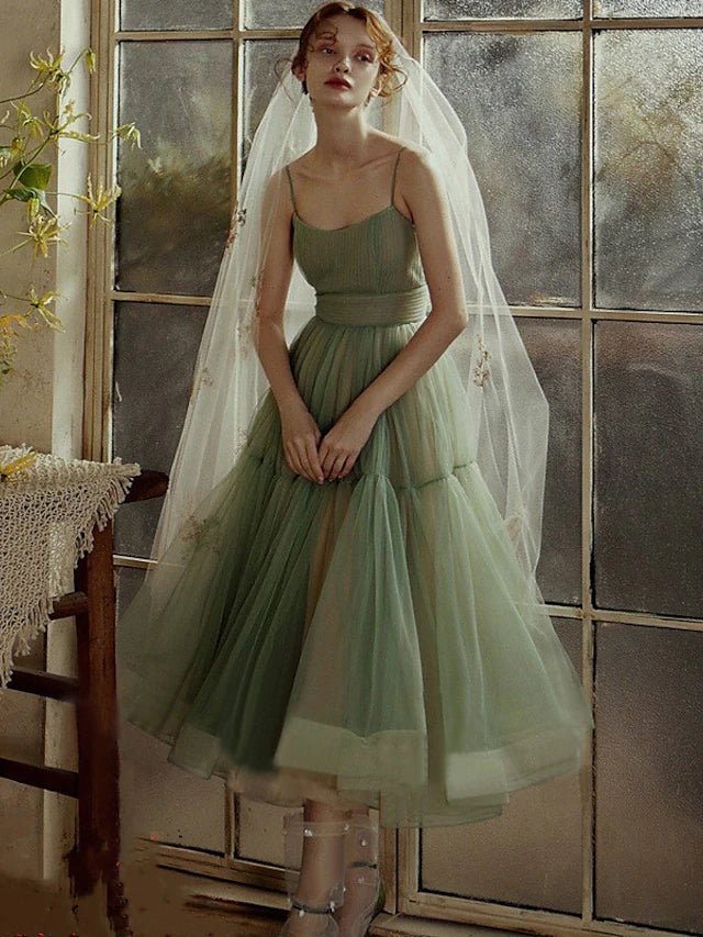 Woman wearing an elegant minimalist tea length tulle dress with spaghetti straps.