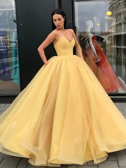 Model wearing an elegant strapless floor-length tulle evening gown with an open back.
