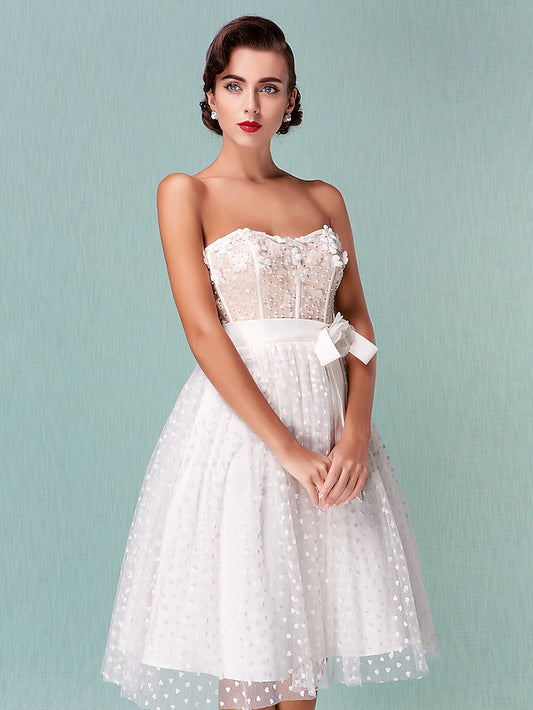 Elegant strapless sweetheart tulle wedding dress with open back and bowknot sash, knee length.