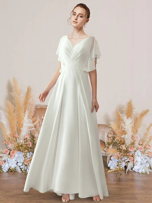 Woman wearing an elegant white A-line V-neck short sleeve chiffon wedding dress with pleats and appliques.