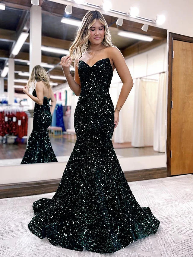 Back view of a woman in a sparkling sequined backless formal gown.